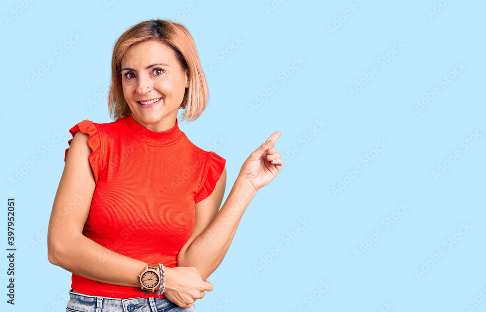 Obraz premium Young blonde woman wearing casual clothes with a big smile on face, pointing with hand and finger to the side looking at the camera.
