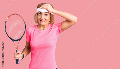 Young blonde woman playing tennis holding racket stressed and frustrated with hand on head, surprised and angry face © Krakenimages.com