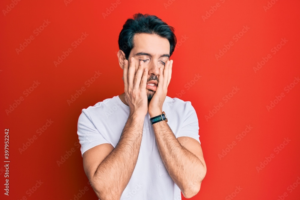 Young hispanic man wearing casual white tshirt tired hands covering face, depression and sadness, upset and irritated for problem Young hispanic man wearing casual white tshirt tired hands covering face, depression and sadness, upset and irritated for problem