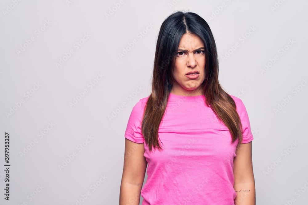 Young beautiful brunette woman wearing casual pink t-shirt standing over white background skeptic and nervous, frowning upset because of problem. Negative person. Young beautiful brunette woman wearing casual pink t-shirt standing over white background skeptic and nervous, frowning upset because of problem. Negative person.