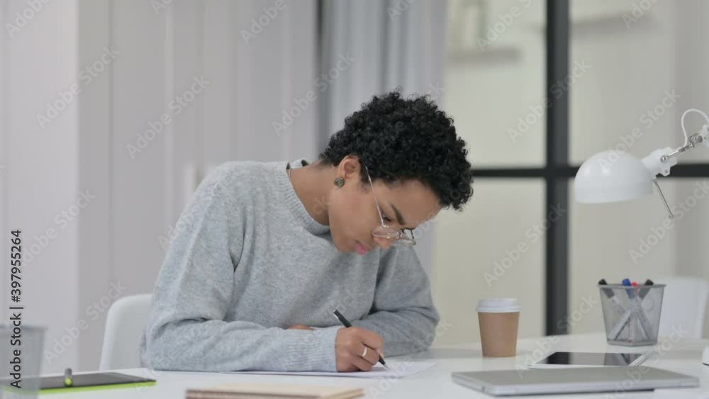 Young African Woman Writing on Paper at Work Young African Woman Writing on Paper at Work