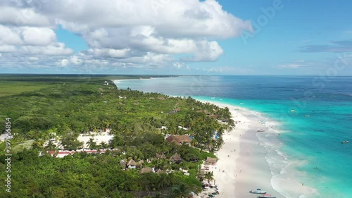 Vista aérea panorámica de la densa jungla tropical que rodea la playa en Tulum, México. Un cielo azul nublado y el mar azul turquesa como fondo.
