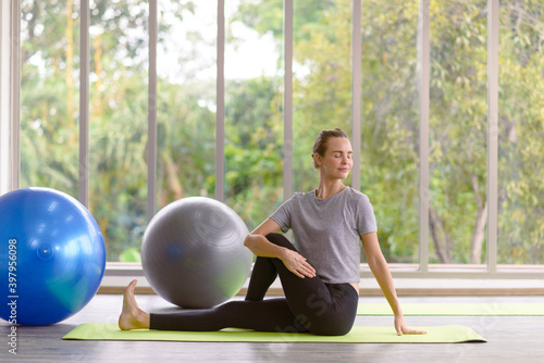 Young beautiful woman practicing yoga lesson on yoga mat, meditating in living room at home. healthy lifestyle concept