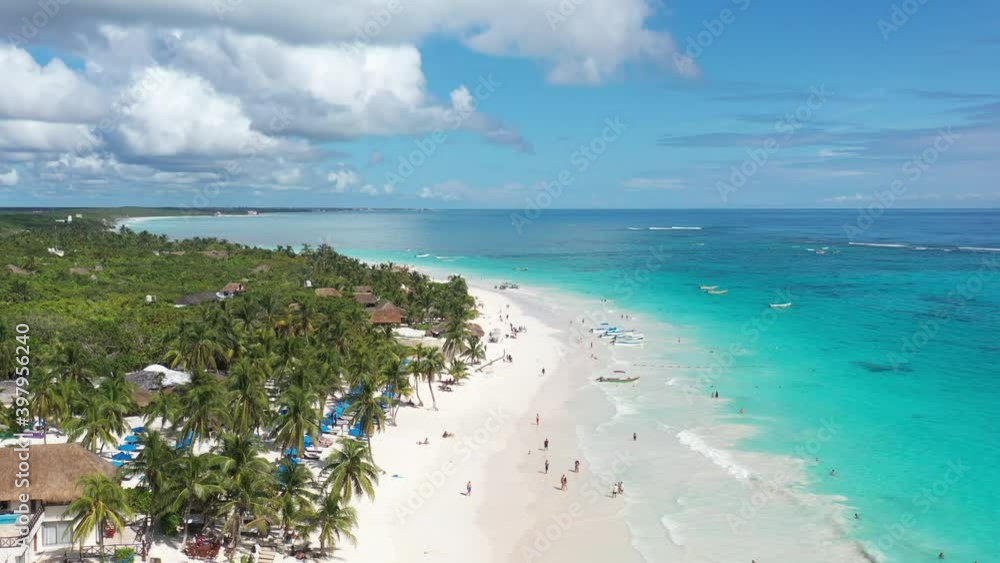 Espectacular vista aérea sobre Playa Paraíso, con muchos turistas caminando sobre la playa y bañándose en el mar, en Tulum, México.