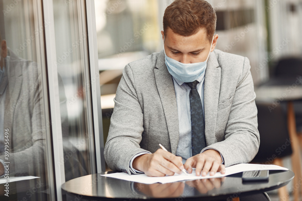 Businessman in a city. Person in a mask. Coronavirus theme. Guy with documents and phone; Businessman in a city. Person in a mask. Coronavirus theme. Guy with documents and phone;
