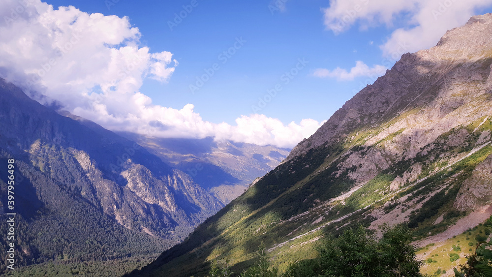 Rocky mountains view in summer day with white clouds in blue sky