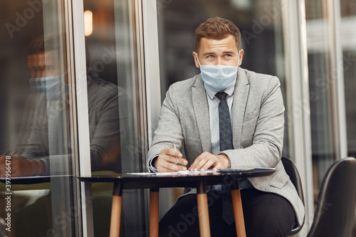 Businessman in a city. Person in a mask. Coronavirus theme. Guy with documents and phone  © hetmanstock2