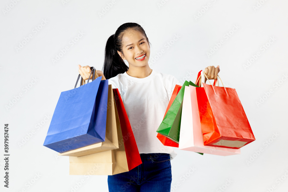 attractive happy smiling asia woman shopaholic in white shirt holding colorful shopping bags on white studio background isolated, sale excited