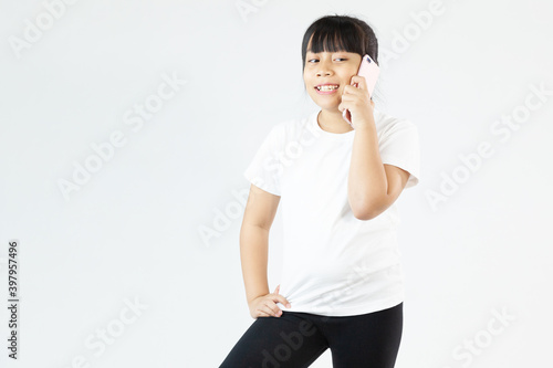 Cute little asia girl talking by mobile phone on white background photo