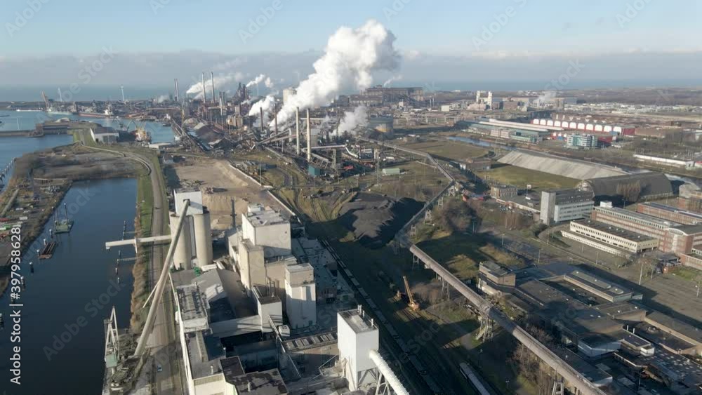 Aerial of distant large steel mill with smoking chimneys Aerial of distant large steel mill with smoking chimneys