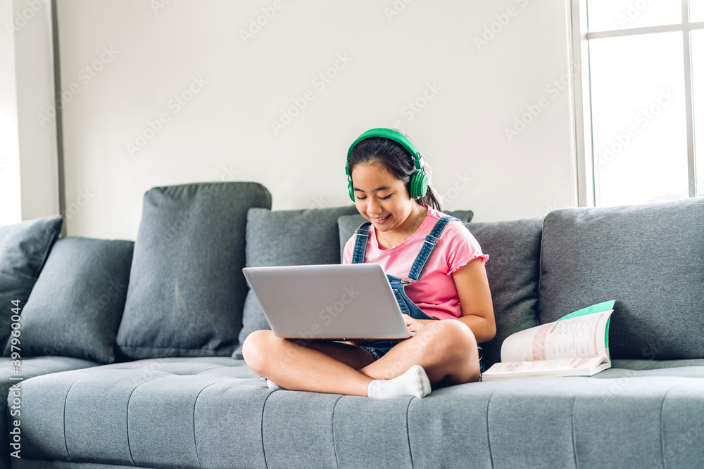School kid little girl learning and looking at laptop computer making homework studying knowledge with online education e-learning system.children video conference with teacher tutor at home School kid little girl learning and looking at laptop computer making homework studying knowledge with online education e-learning system.children video conference with teacher tutor at home
