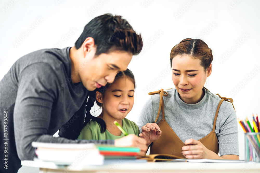 Portrait enjoy happy smiling love asian family father and mother with little asian girl learning and writing in book with pencil making homework at home.Education concept Portrait enjoy happy smiling love asian family father and mother with little asian girl learning and writing in book with pencil making homework at home.Education concept