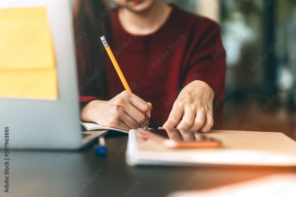 Young adult women hand writing note for study and work online at cafe table with laptop. Young adult women hand writing note for study and work online at cafe table with laptop.