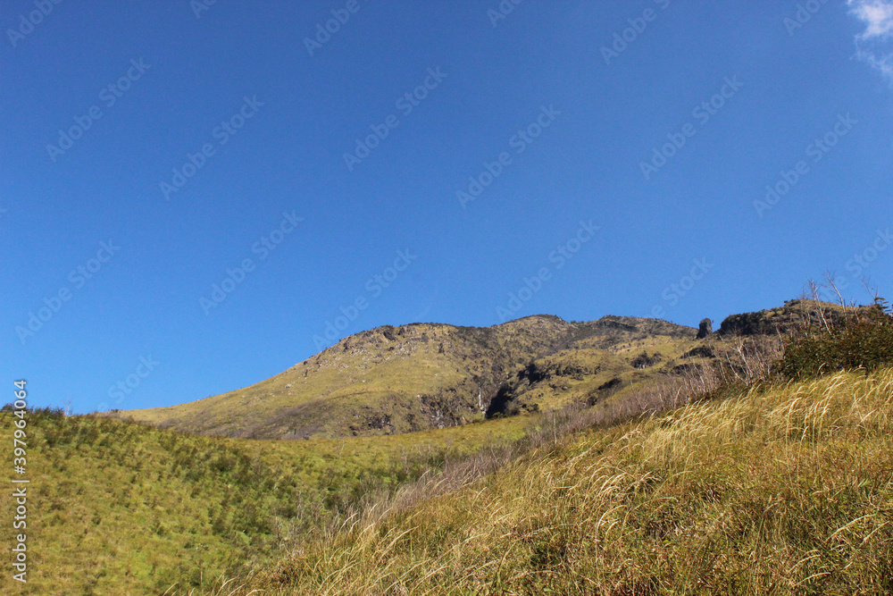 beautiful meadow landscape with blue sky, sunny day weather, rock hill on sumbing mountain in java indonesia, wildlife nature background wallpaper photo beautiful meadow landscape with blue sky, sunny day weather, rock hill on sumbing mountain in java indonesia, wildlife nature background wallpaper photo
