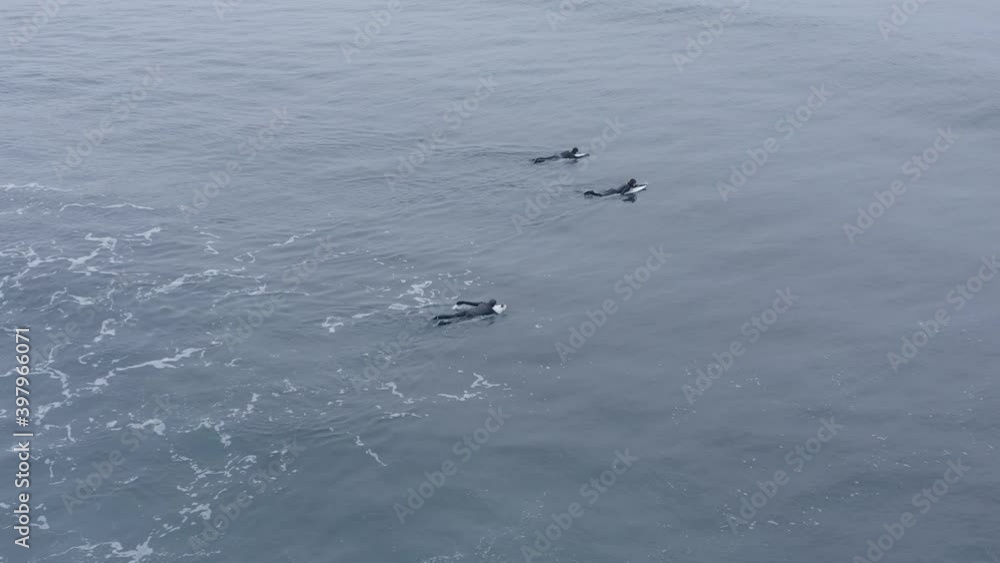 Surfers floating in water on surfboard paddling back to lineup, aerial Surfers floating in water on surfboard paddling back to lineup, aerial