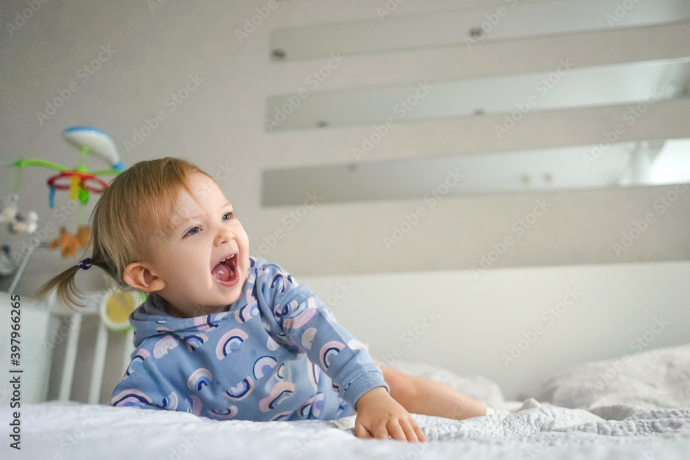 Adorable little smiling girl in beautiful suit at home on bed. Light and white interior. Adorable little smiling girl in beautiful suit at home on bed. Light and white interior.