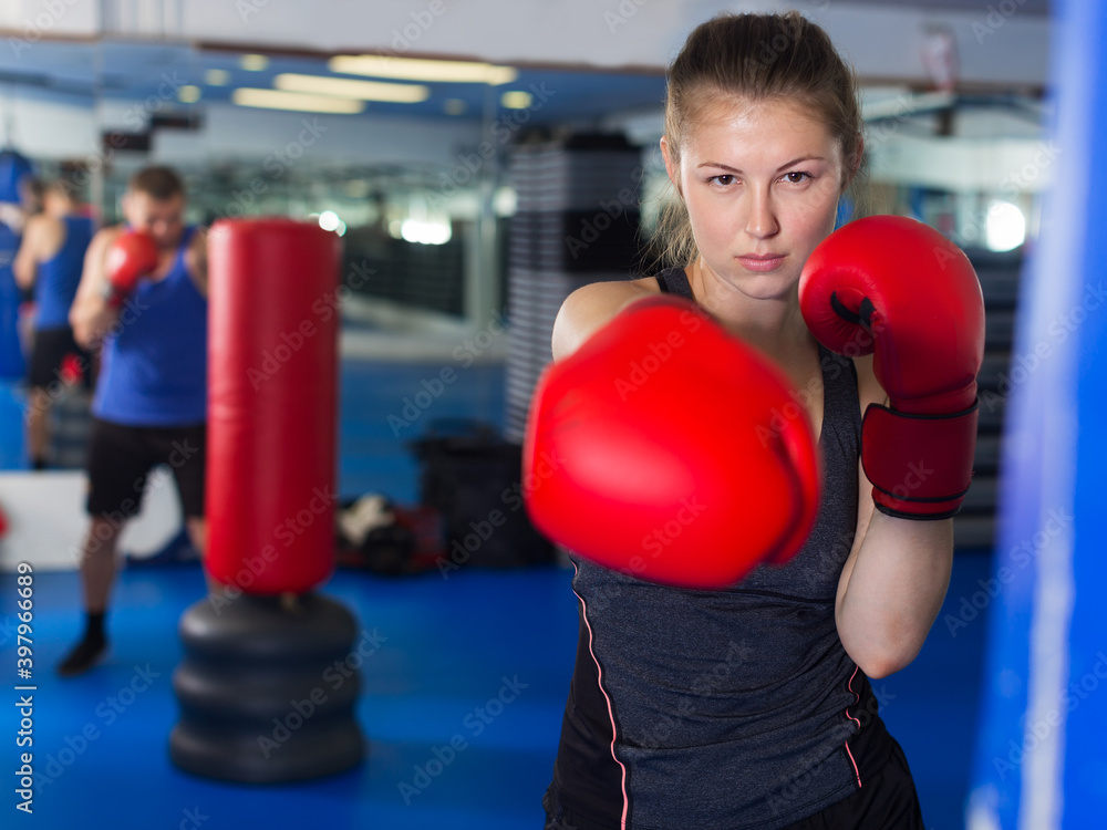 Portrait of young positive woman who is boxing in fitness center