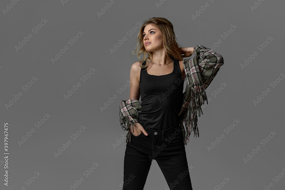Fototapeta premium portrait of beautiful blonde woman with curly hair in jacket on chair on studio background. copy space