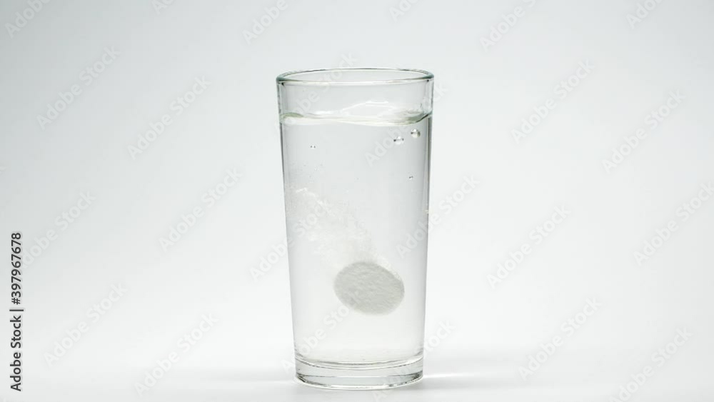 Slow motion closeup aspirin medicine pill, vitamin in glass of water, bubbles Slow motion closeup aspirin medicine pill, vitamin in glass of water, bubbles