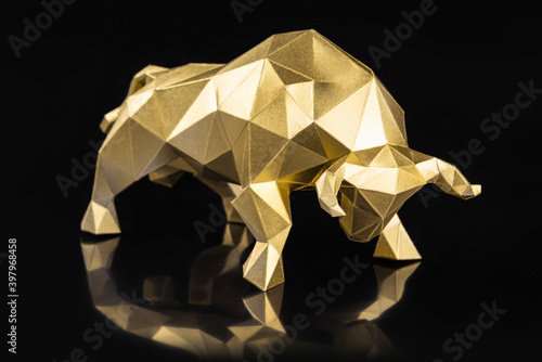 Golden volumetric paper bulll on a black glossy background, symbol of the year photo