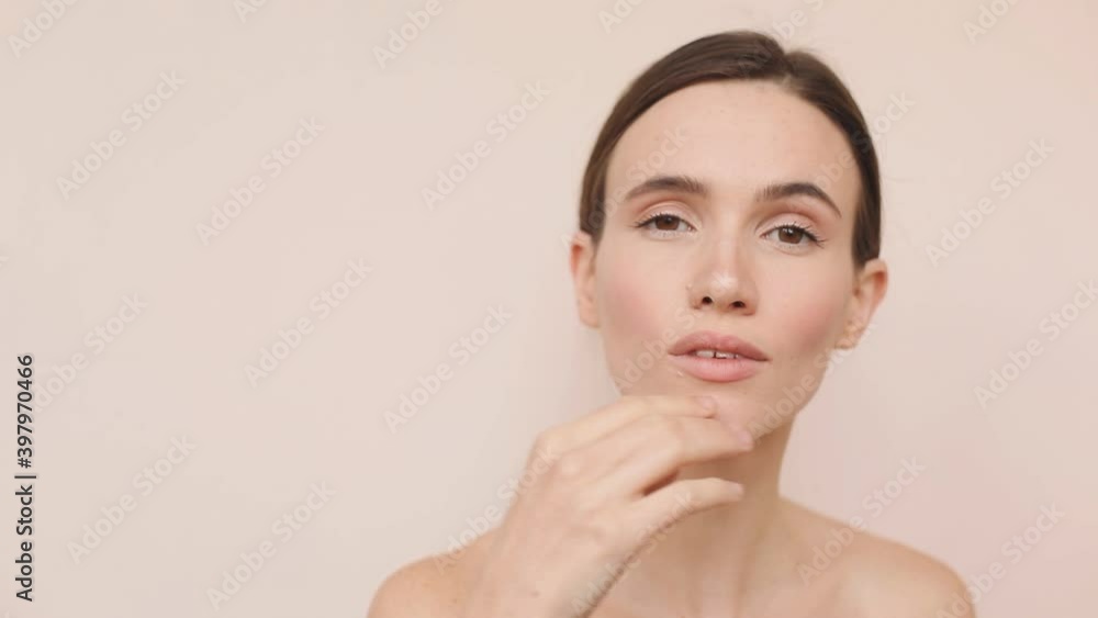 Skin care treatment or cosmetic ads concept. Beautiful female model with perfect fresh and clean skin. She gently touches her face with her finger on face color background and look sensual. Skin care treatment or cosmetic ads concept. Beautiful female model with perfect fresh and clean skin. She gently touches her face with her finger on face color background and look sensual.