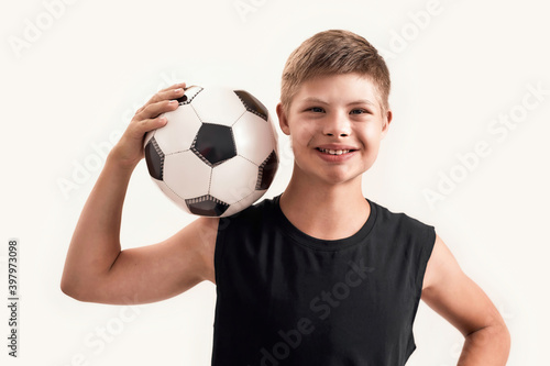Happy disabled boy with Down syndrome smiling at camera while posing with football isolated over white background © Svitlana