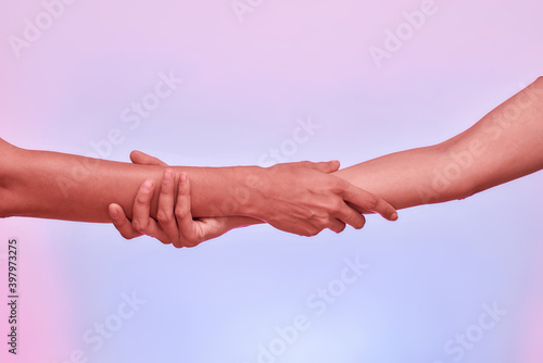 Close up of two girls, sisters holding each other arm isolated over purple background. Support, togetherness concept