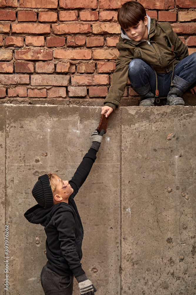 Φωτογραφία friendly child give a piece of bread to his street boy friend, street children want to eat, on city street
