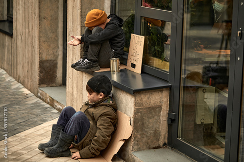 sad orphans children begging in town streets, it's cold outdoors, need shelter and monety to survive photo