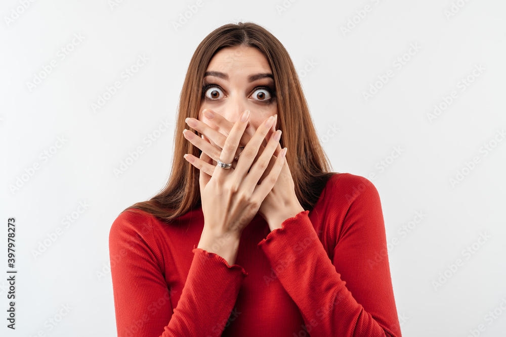 Image of young scared woman covering her mouth with hands. Fright, phobia and facial expression concept Image of young scared woman covering her mouth with hands. Fright, phobia and facial expression concept