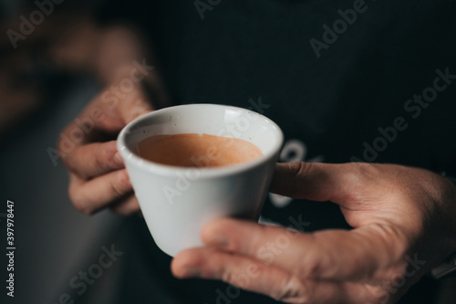 A cup of hot espresso in a male hands - a breath of energy and freshness in the early morning - a boost of vivacity for the day