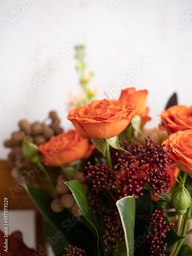 Bouquet of fresh flowers of spray roses of coral color  dianthus and various plants on a vintage wooden chair on a light background in the morning light