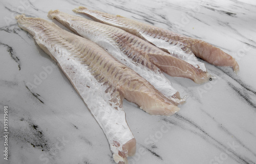 Gastronomy. Fresh seafood ingredients for cooking. Closeup view of raw Patagonias hake filets on the white kitchen table.