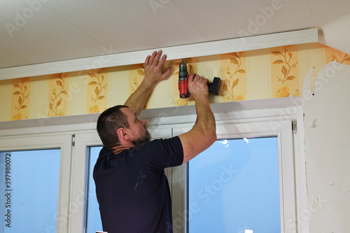 An adult man works with a screwdriver in a room. Home renovation concept.