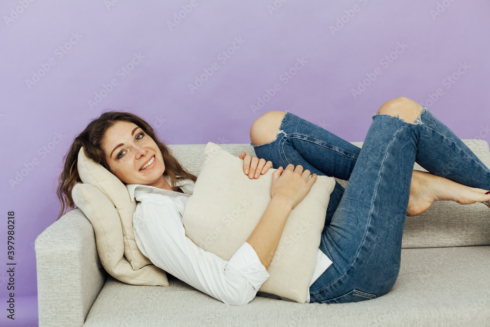 Beautiful woman sits on a gray office sofa in a white house room