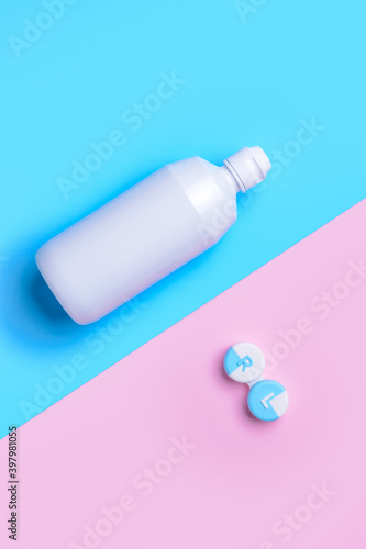 Container with contact lenses and solution on color background