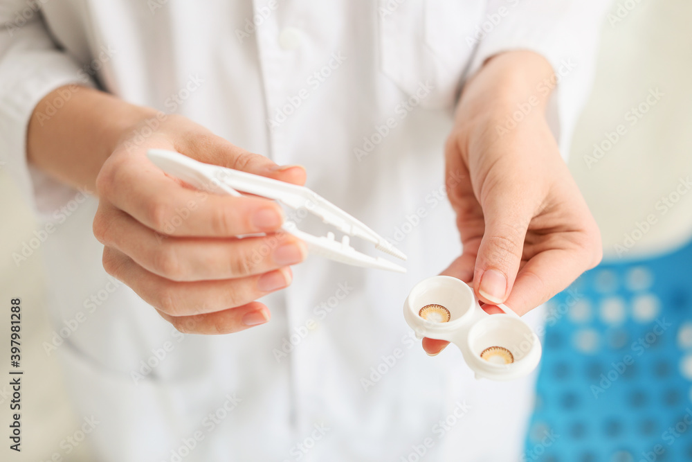 Woman holding container with contact lenses and tweezers in clinic Woman holding container with contact lenses and tweezers in clinic