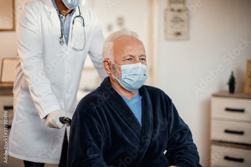 Senior man in wheelchair wearing protective face mask at nursing home.