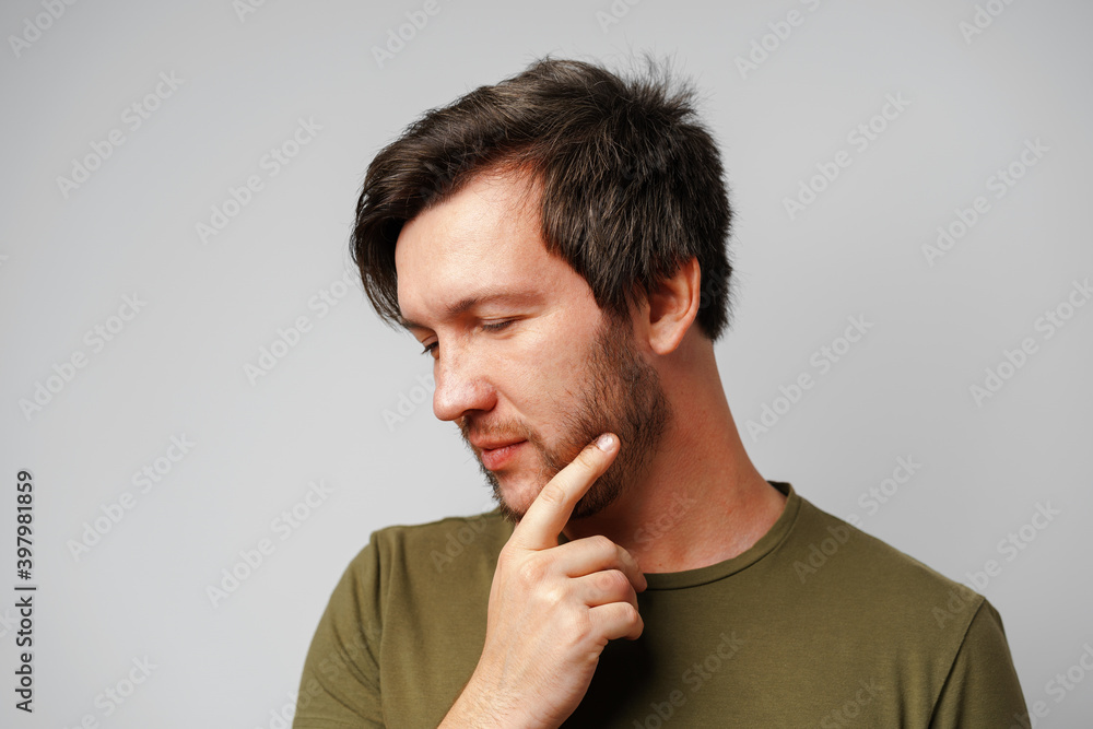 Portrait of a serious pensive young man against grey background