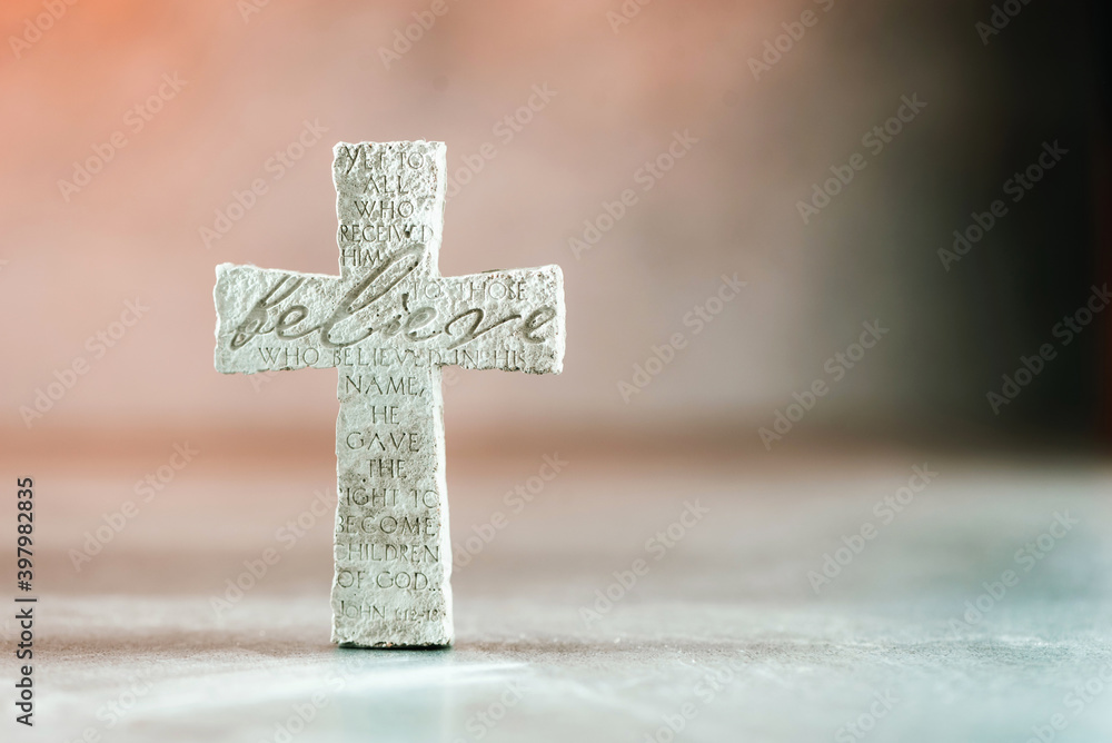 Naklejka premium Stone cross with inscription Believe on grey background, Copy space. Christian backdrop. Biblical faith, gospel, salvation concept