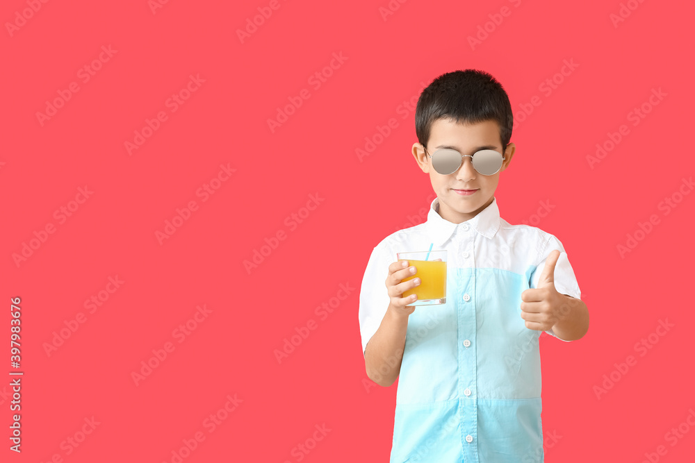 Cute boy with stylish sunglasses and fresh juice showing thumb-up against color background Cute boy with stylish sunglasses and fresh juice showing thumb-up against color background