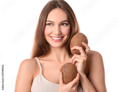 Beautiful young woman with coconuts on white background