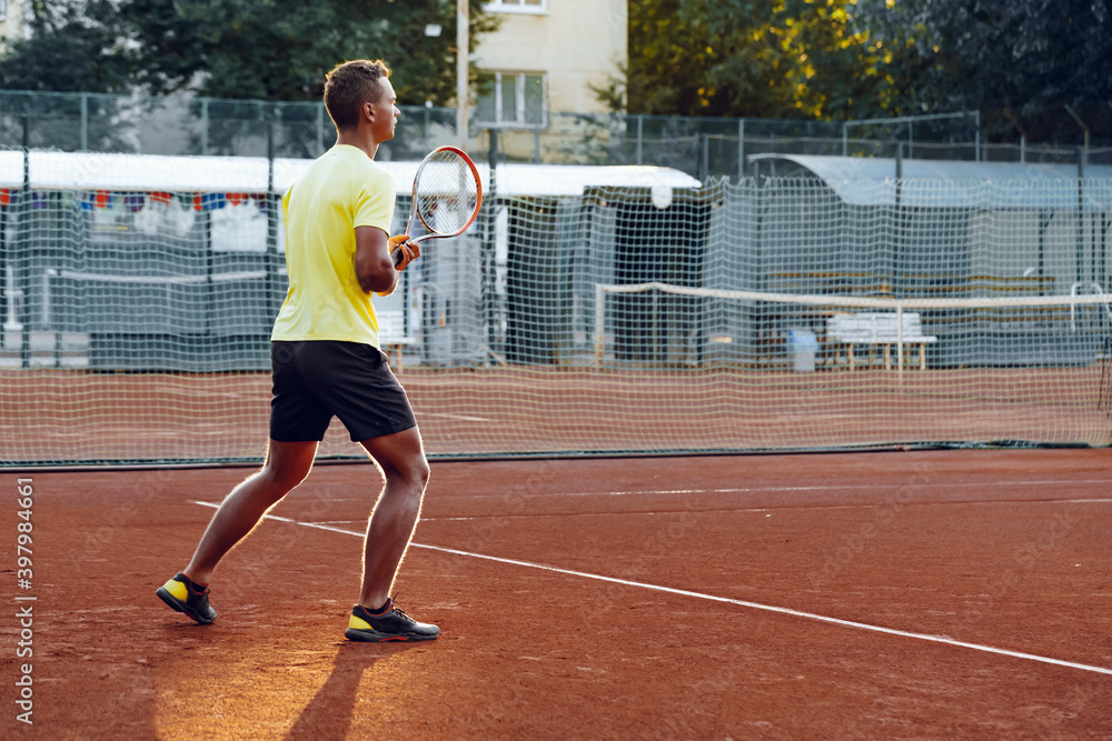 Obraz premium Young handsome man playing tennis on the tennis court