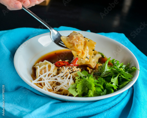 Boiled meat dumplings with fresh parsley, soy sauce and sesame seeds. Delicious meal for dinner. photo