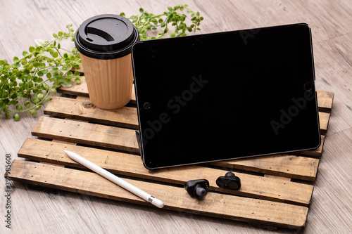 飲み物と黒いイヤホンとタブレット端末が木製の机に置いてある　tablet cofee earphon photo