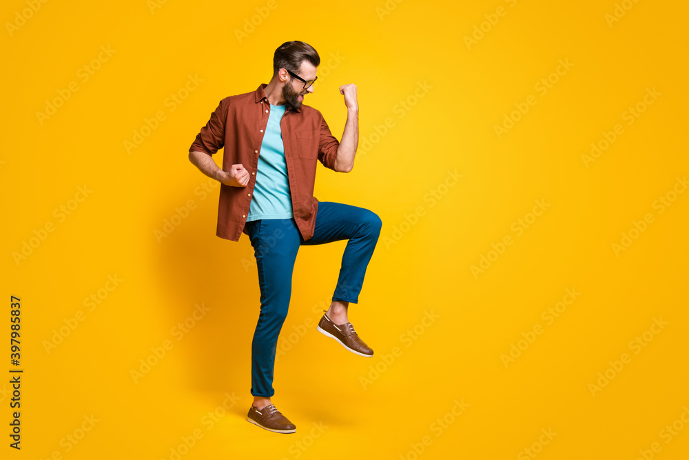 Full length body size photo of happy man in casual outfit gesturing like winner isolated on vivid yellow color background Full length body size photo of happy man in casual outfit gesturing like winner isolated on vivid yellow color background