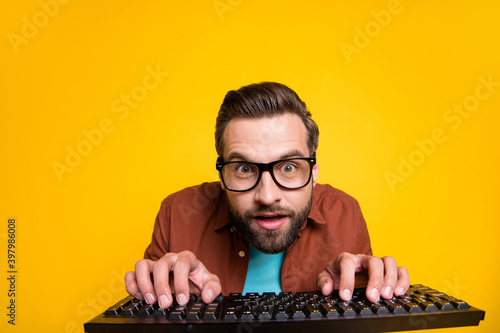 Photo portrait of bearded student playing video game crazy geek with keyboard in glasses isolated on vibrant yellow color background photo
