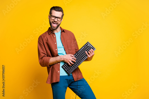 Photo portrait of bearded man keeping keyboard playing like guitar isolated on bright yellow color background