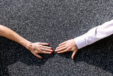 Close-up of a couple touching hands against the wall.