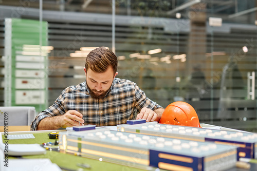 caucasian architect engineer man is concentrated on designing building and ther structures, she is scrupulously working on the project with 3d model photo